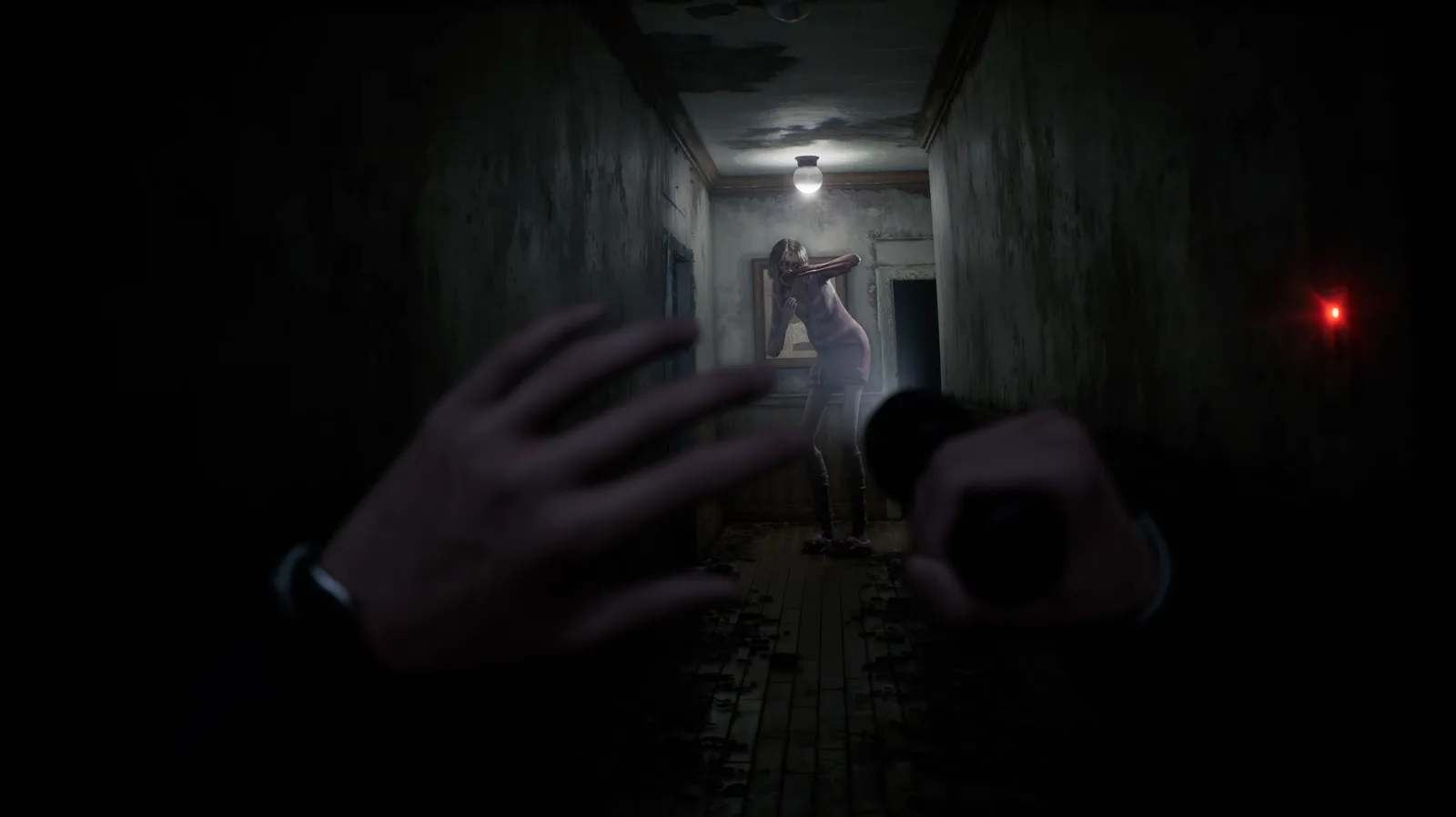 El detective de Rehaunted alumbra con su linterna un pasillo en ruinas mientras la entidad lo observa desde el fondo